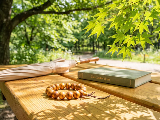  A golden sandalwood bead bracelet resting on a wooden table beneath green tree leaves.