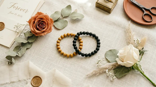 A stunning wedding flat lay featuring Lumala's golden sandalwood and matte black ebony wood bead bracelets, styled with a terracotta rose, an ivory bouquet, and eucalyptus leaves for a 2026 boho chic wedding palette.