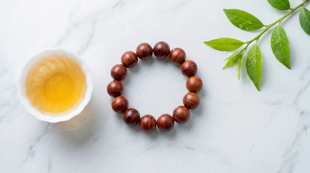 Red sandalwood bracelet on white marble with a cup of tea and green leaves