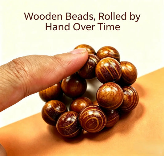 A hand rolling a wooden bead bracelet between the fingers, showing the natural grain of the polished beads — the traditional pan wan rolling practice from China.