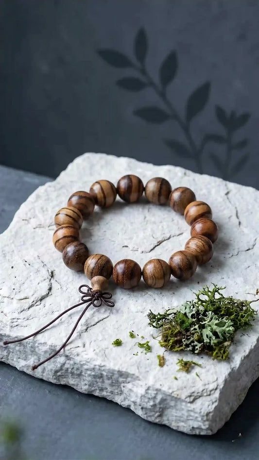 Minimalist Wabi-Sabi wenge wood striped bracelet on a light concrete countertop next to a ceramic vase with a dry branch and subtle incense 